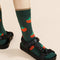 up close of model wearing green crew socks with all over tomato prints