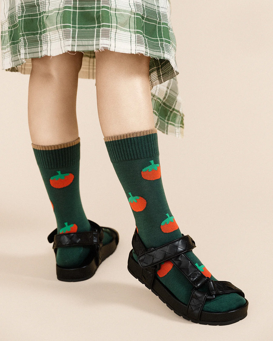 model wearing green crew socks with all over tomato prints