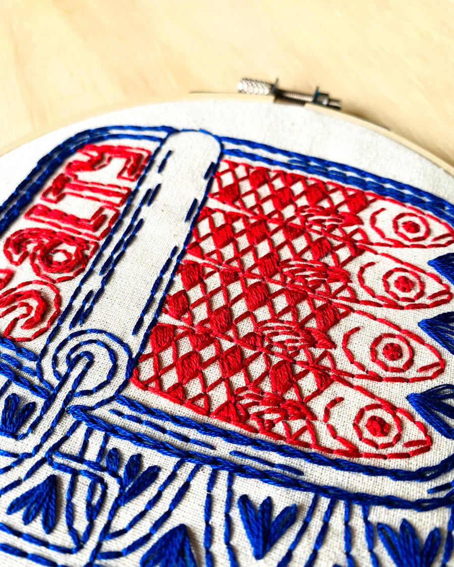 up close of red and blue tin sardine embroidery kit