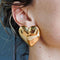 model wearing large gold puffy hearts stud earrings