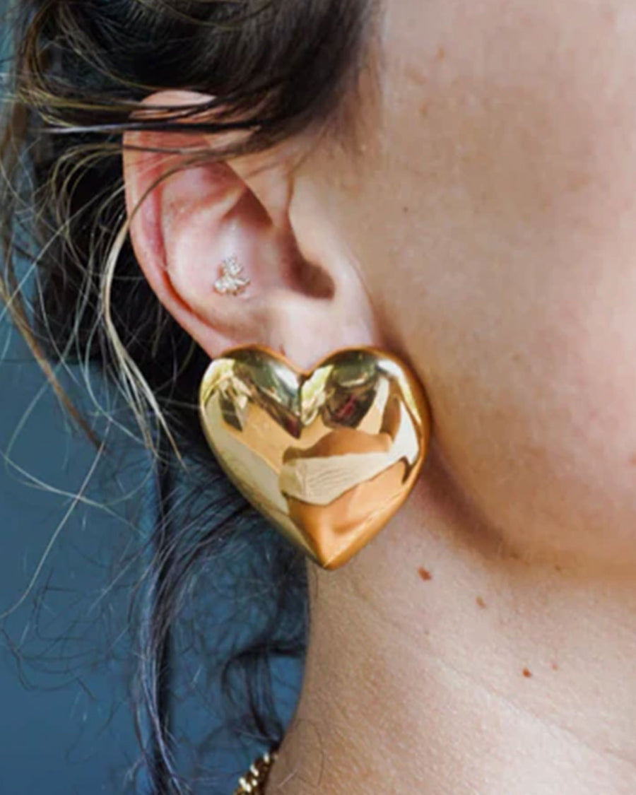 model wearing large gold puffy hearts stud earrings