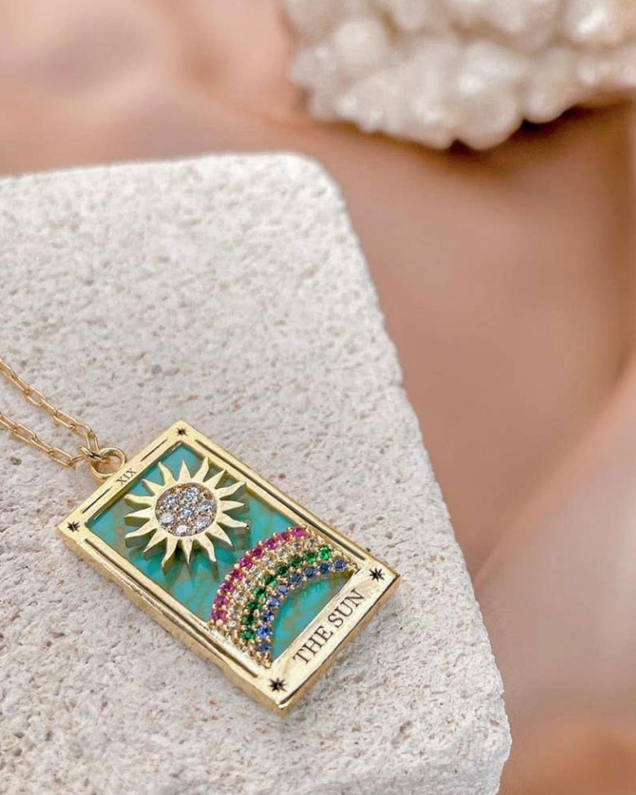 side view of gold sun tarot card necklace with colorful crystals 