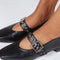 up close of model wearing black mary jane flats with elastic back and thick buckle strap with silver grommets and buckle