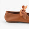 back view of camel colored flats with tie buckle