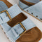 up close of light denim platform slide sandal with brass buckles