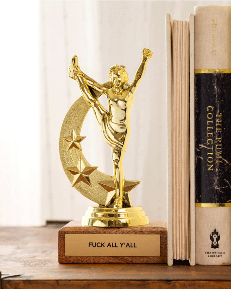 'f*ck all y'all' gold trophy on a shelf