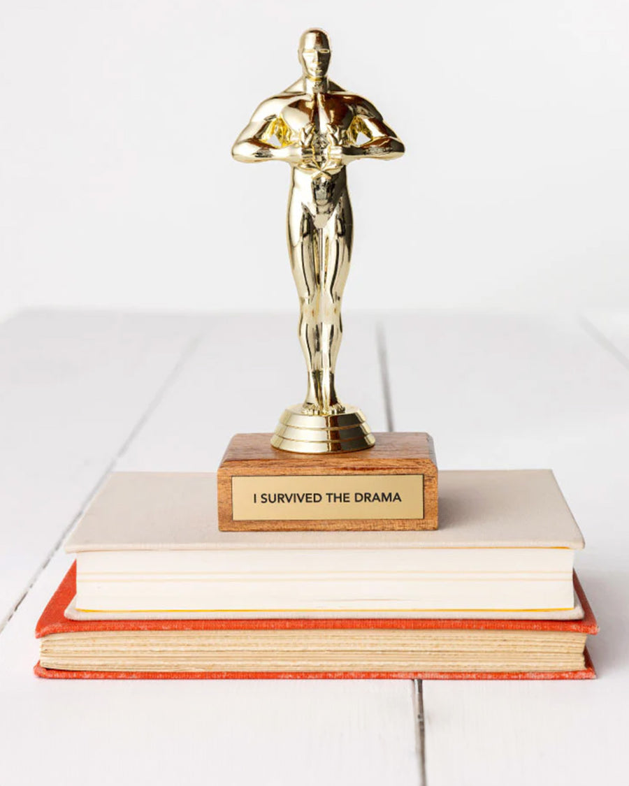 'i survived the drama' gold trophy on a stack of books