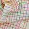 close view of cream tea towel with colorful thin plaid print