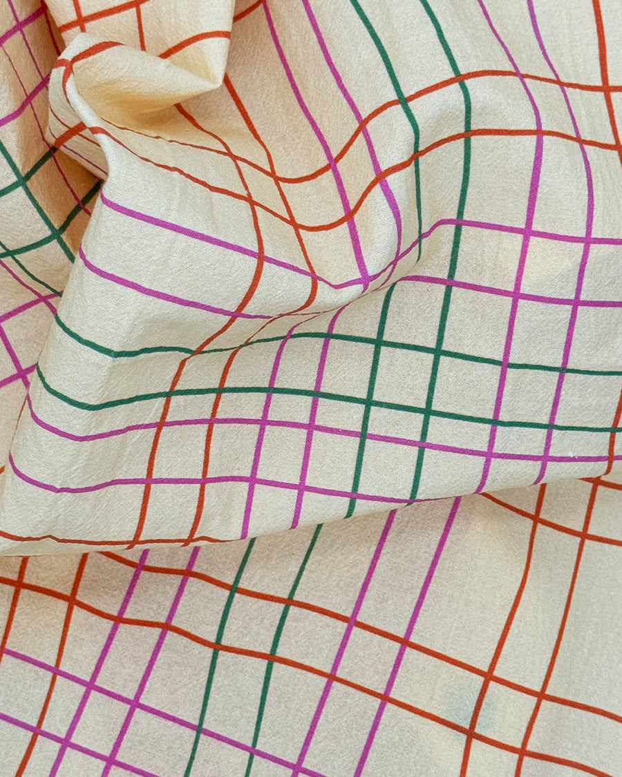 close view of cream tea towel with colorful thin plaid print