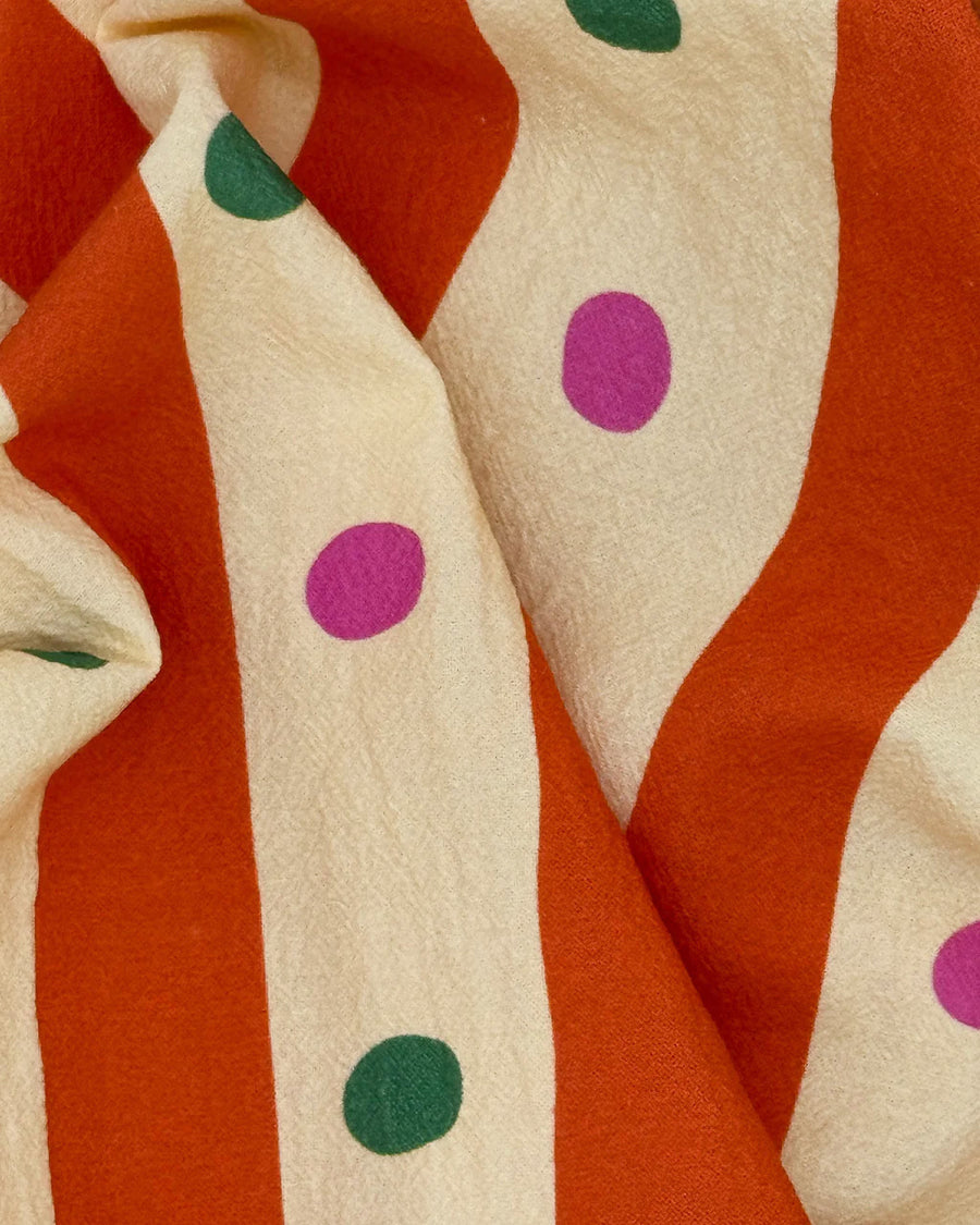 up close of pale yellow and orange striped tea towel with green and pink dots