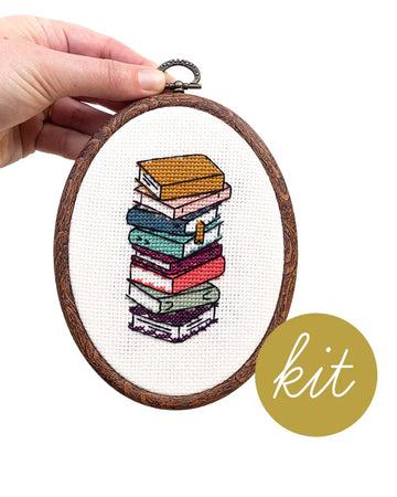 model holding stacked books embroidered cross stitch kit