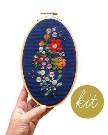 model holding blue cross stitch kit with colorful flowers