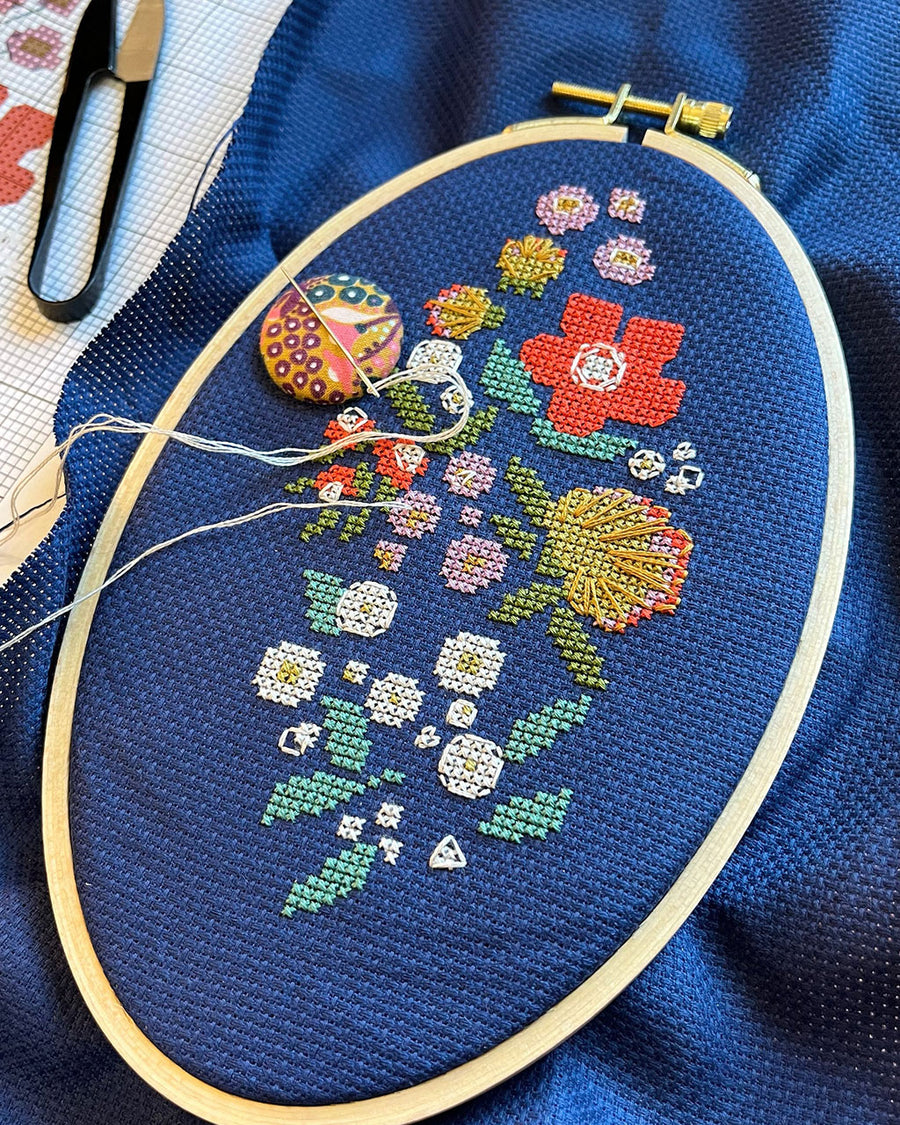 incomplete blue cross stitch kit with colorful flowers