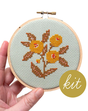 model holding light blue embroidered cross stitch kit  with yellow flowers