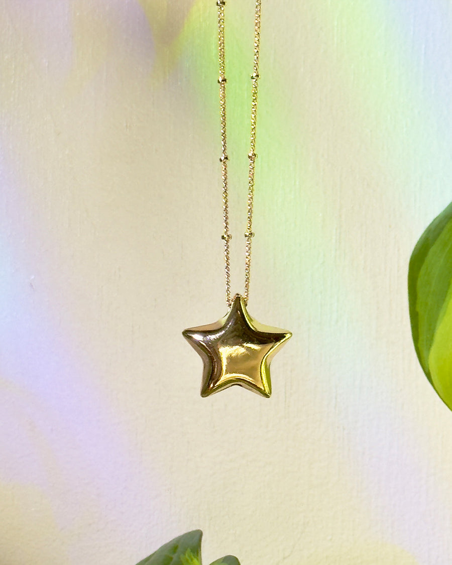 up close of gold star shaped pendant necklace