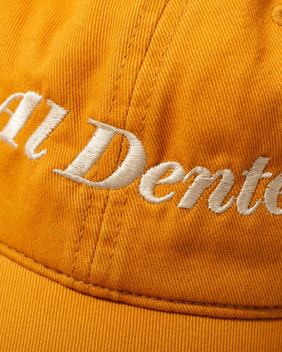 up close of yellow baseball hat with cream embroidered 'al dente' across the front