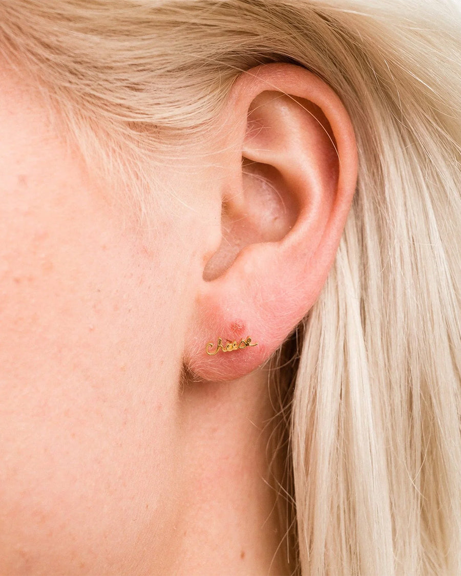 model wearing gold cursive 'cheese' single stud earring