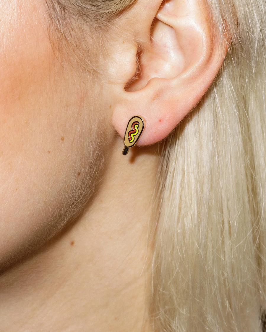 model wearing pair of corn dog with ketchup and mustard enamel earrings