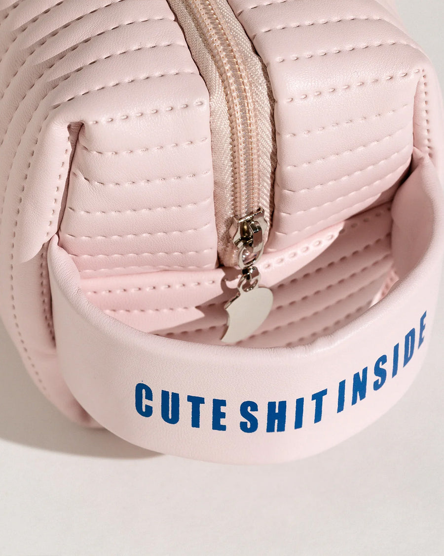 up close of pink quilted bag with 'cute shit inside' on the handle