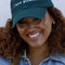 model wearing dark green baseball hat with white embroidered 'i love pickles' across the front