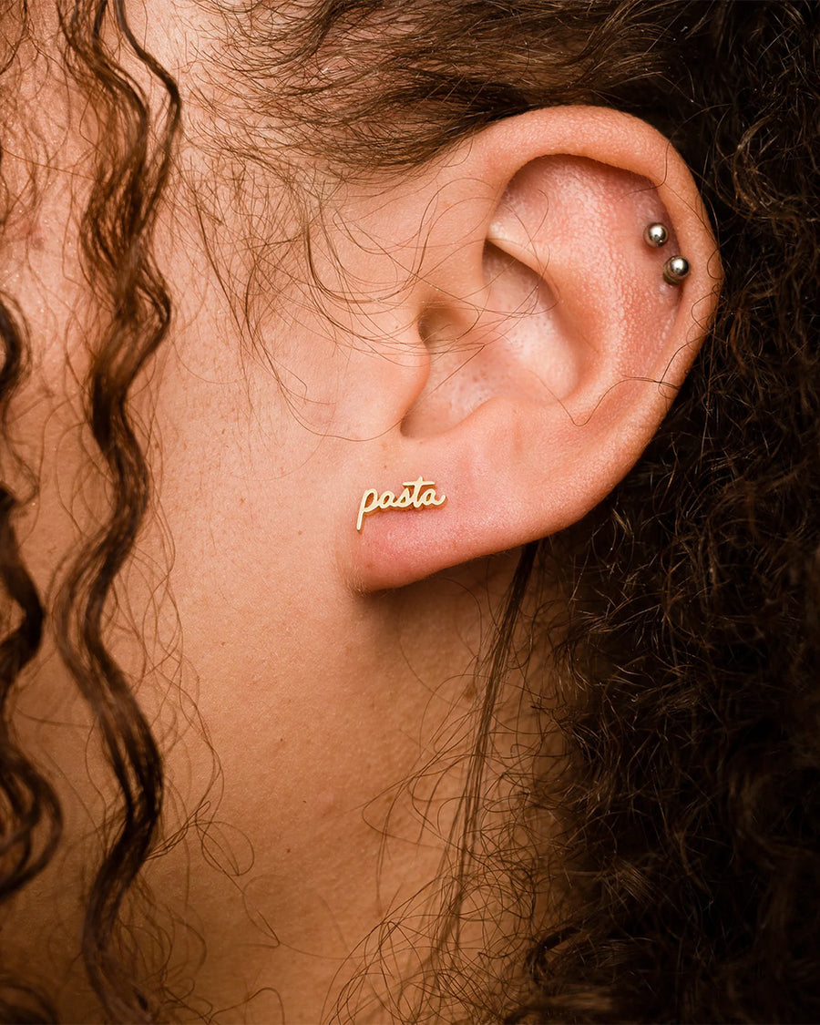 model wearing gold cursive 'pasta' single stud earring