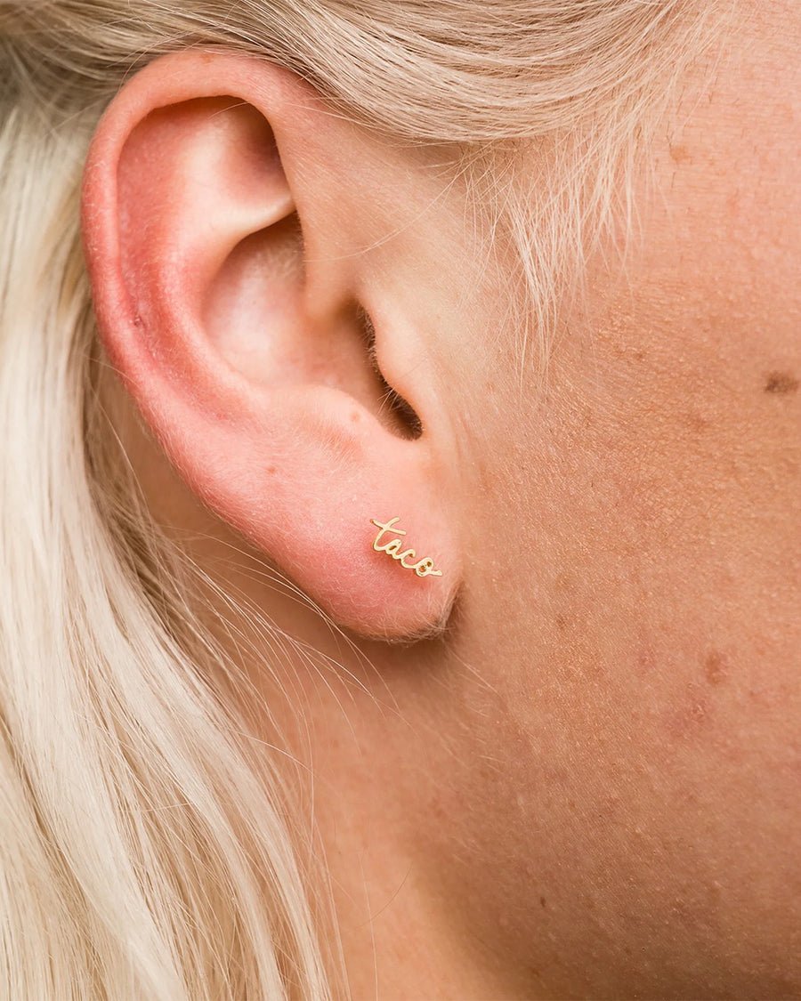 model wearing gold cursive 'taco' single stud earring