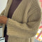 up close of model wearing sand chunky knit open front cardigan with front patch pockets