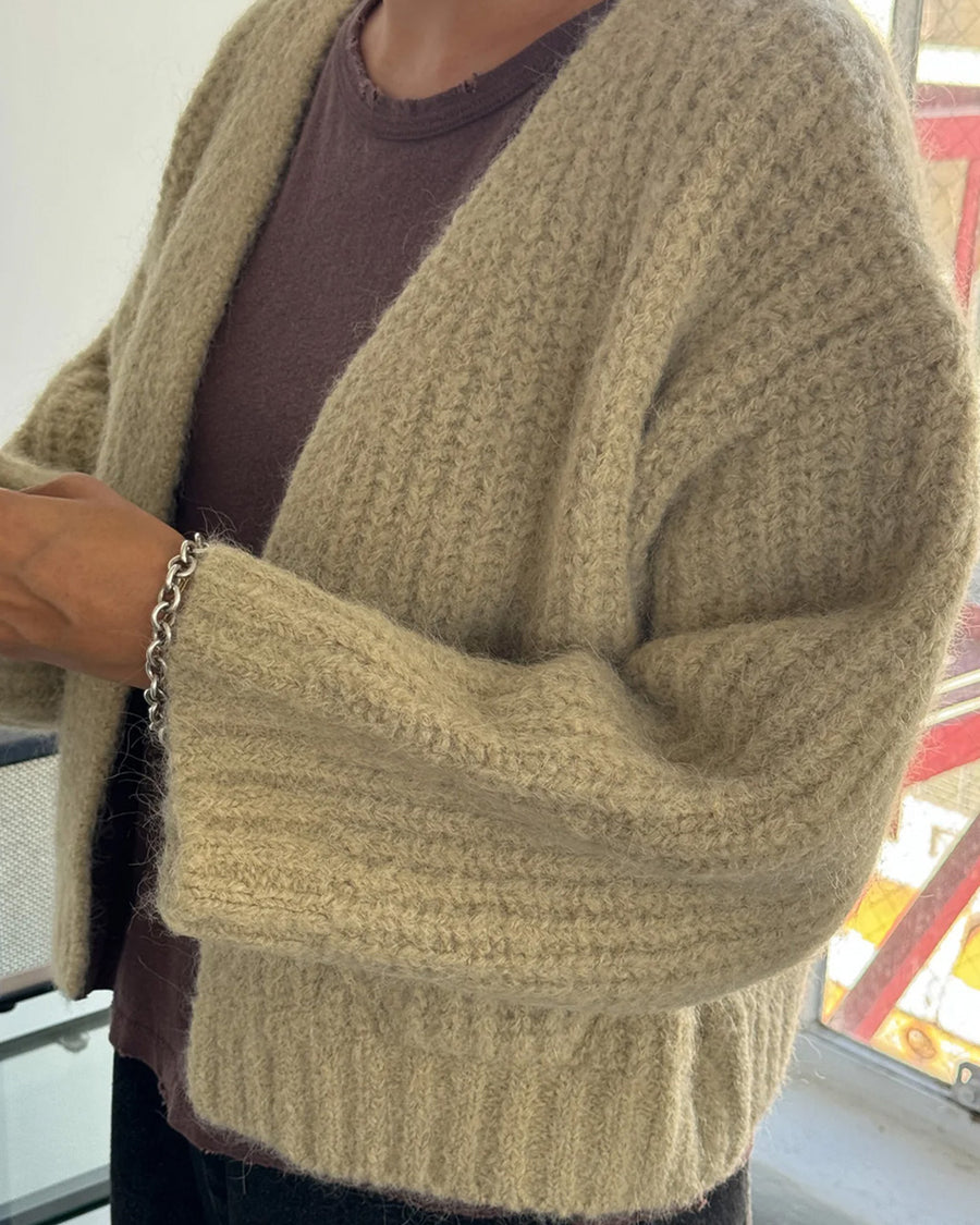 up close of model wearing sand chunky knit open front cardigan with front patch pockets