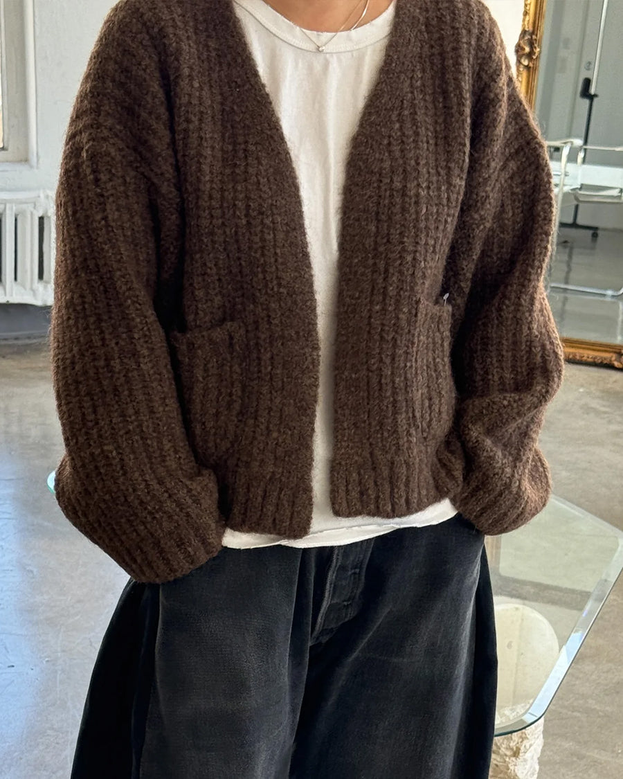 model wearing dark brown chunky knit open front cardigan with front patch pockets