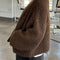 side view of model wearing dark brown chunky knit open front cardigan with front patch pockets