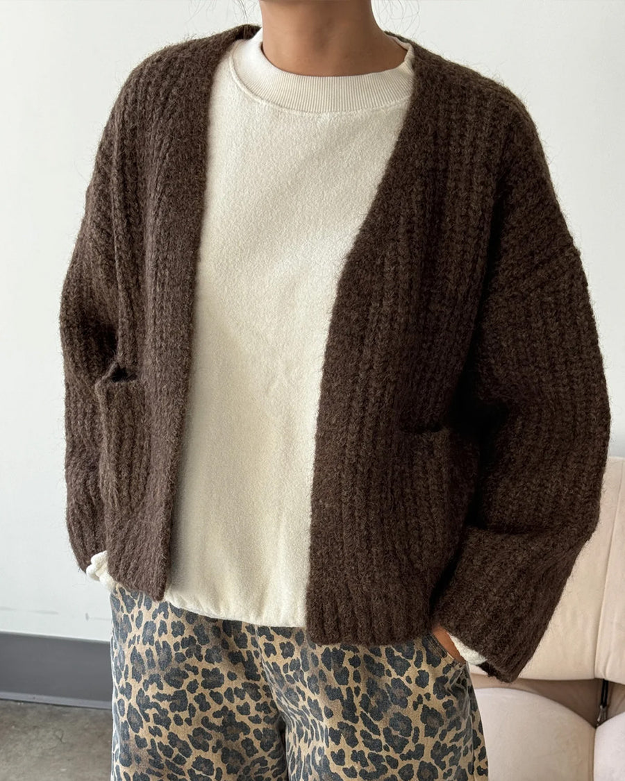 model wearing dark brown chunky knit open front cardigan with front patch pockets