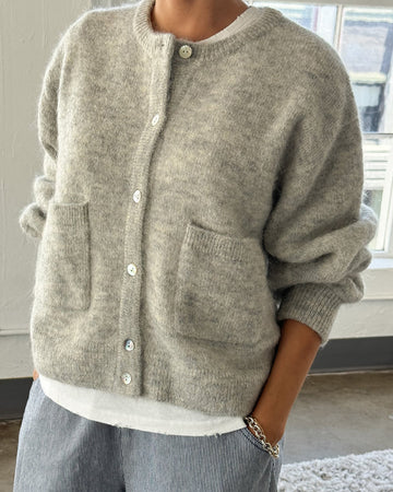 model wearing light grey cardigan with white button front and front patch pockets