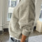 side view of model wearing light grey cardigan with white button front and front patch pockets