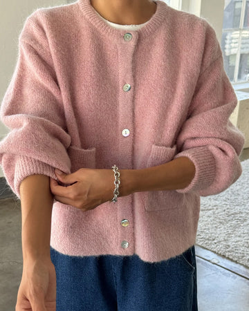 model wearing pink rose cardigan with white button front and front patch pockets