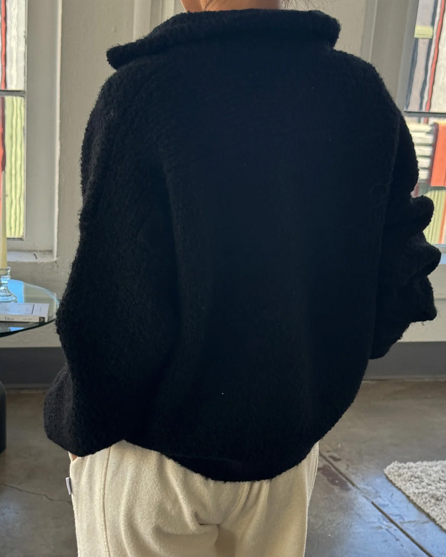 back view of model wearing black fuzzy quarter zip pullover