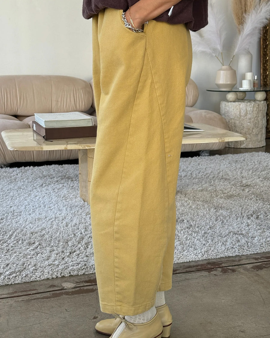 side view of model wearing butter colored cotton canvas barrel pants with side inlets