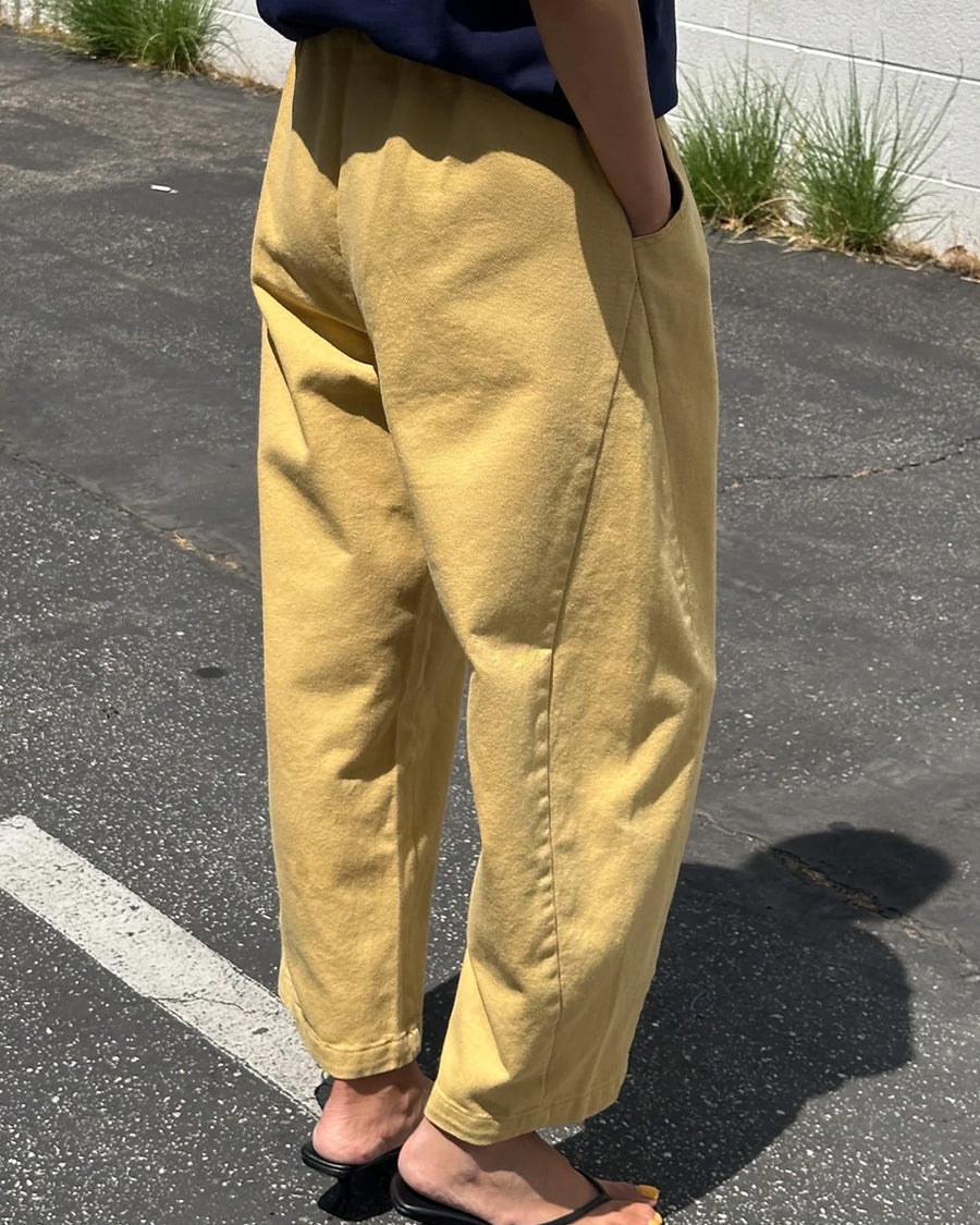 back view of model wearing butter colored cotton canvas barrel pants with side inlets