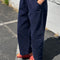 side view of model wearing navy colored cotton canvas barrel pants with side inlets