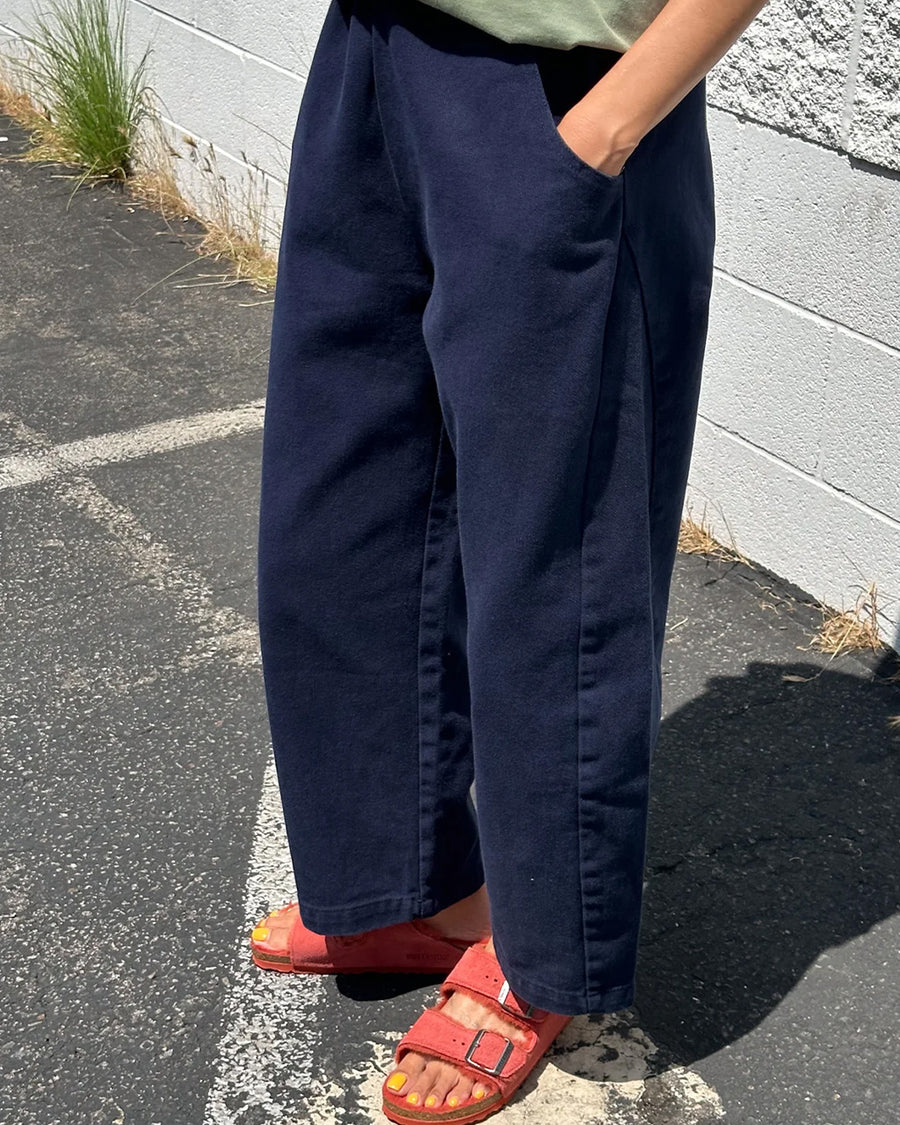 side view of model wearing navy colored cotton canvas barrel pants with side inlets