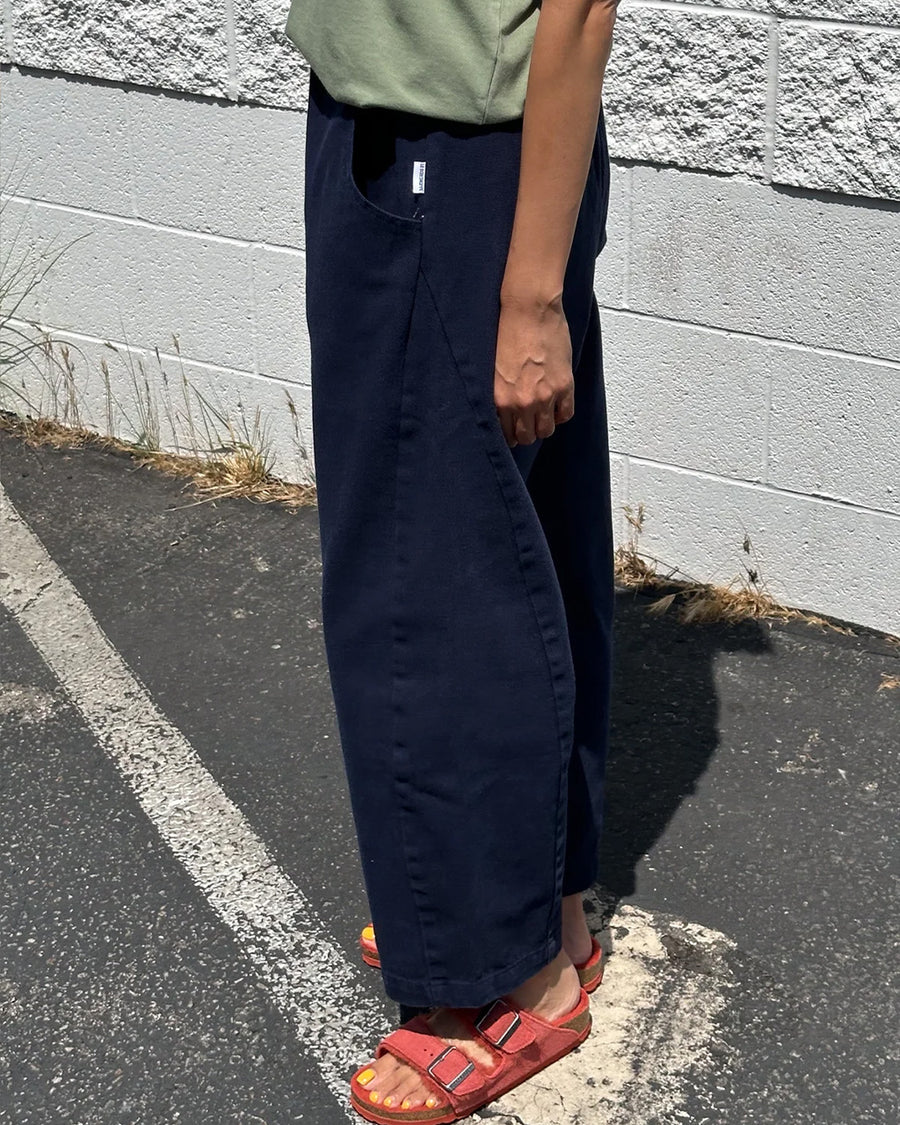 side view of model wearing navy colored cotton canvas barrel pants with side inlets