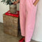 side view of model wearing bubblegum pink cotton pants with slight balloon legs and side pockets