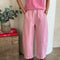 front view of model wearing bubblegum pink cotton pants with slight balloon legs and side pockets