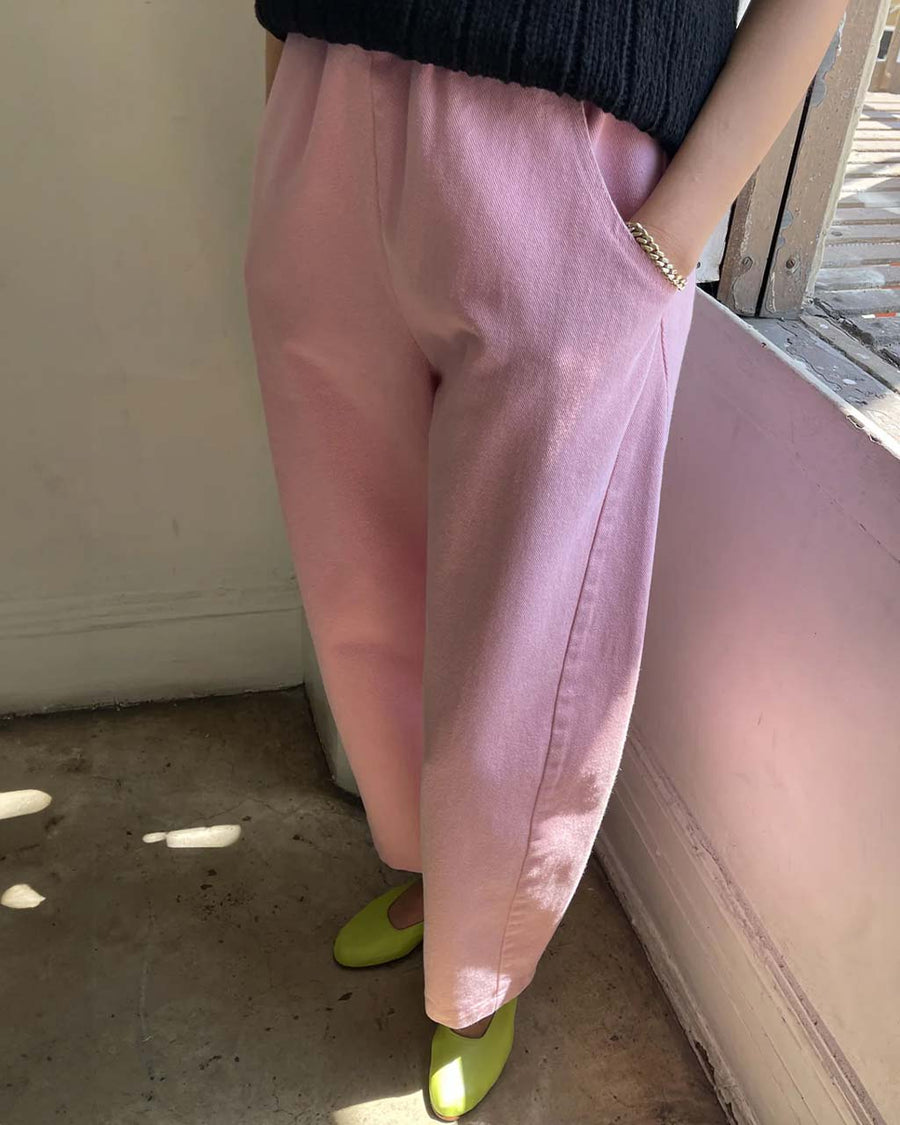model wearing bubblegum pink cotton pants with slight balloon legs and side pockets