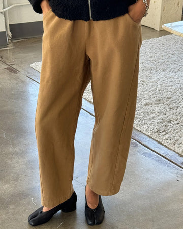 model wearing light brown cotton pants with paneling on the sides