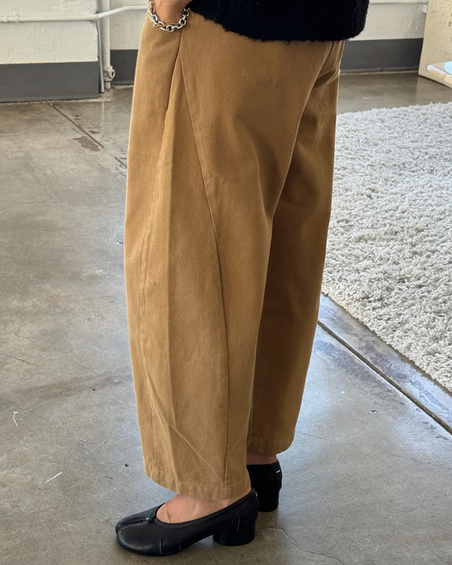 side view of model wearing light brown cotton pants with paneling on the sides