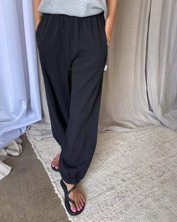 model wearing black cotton balloon pants with elastic at ankles and side pockets