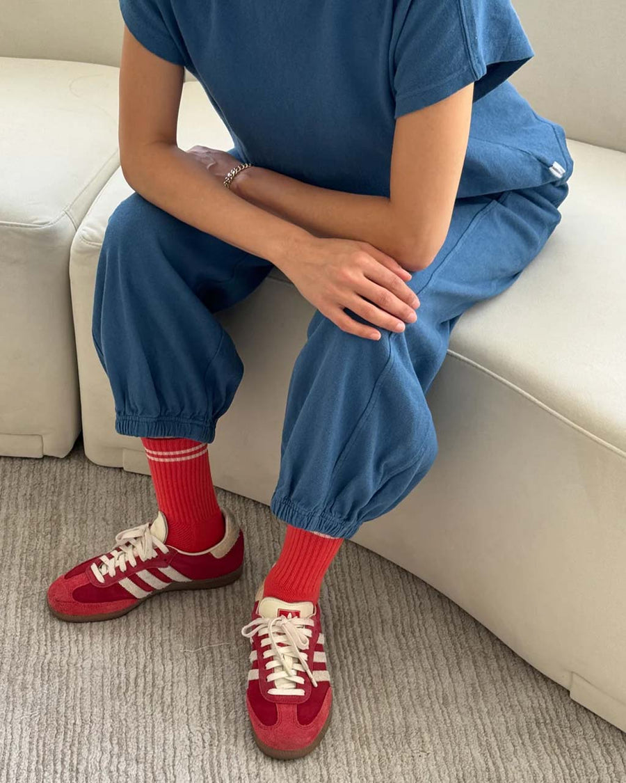 model sitting on couch wearing ocean blue cotton balloon pants with slit side pockets