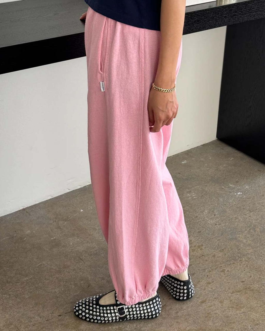 side view of model wearing bubblegum pink cotton balloon pants with slit side pockets