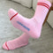 bottom view of model wearing bright pink tube socks with red stripe detail