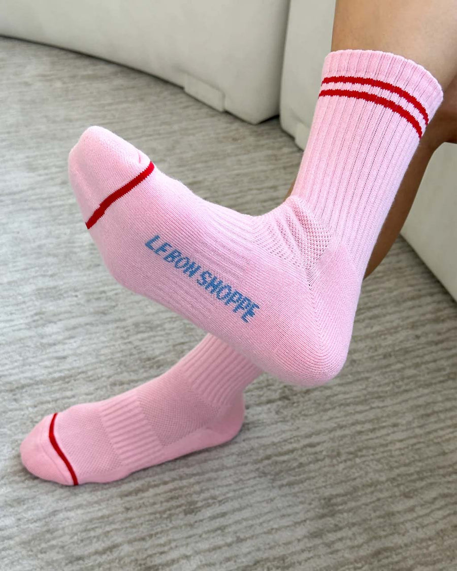 bottom view of model wearing bright pink tube socks with red stripe detail